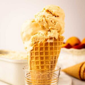Prepared Peach Ice Cream Recipe scooped onto a cone.