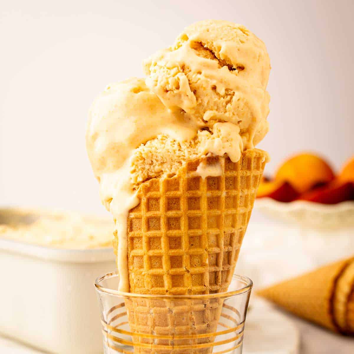 Prepared Peach Ice Cream Recipe scooped onto a cone.