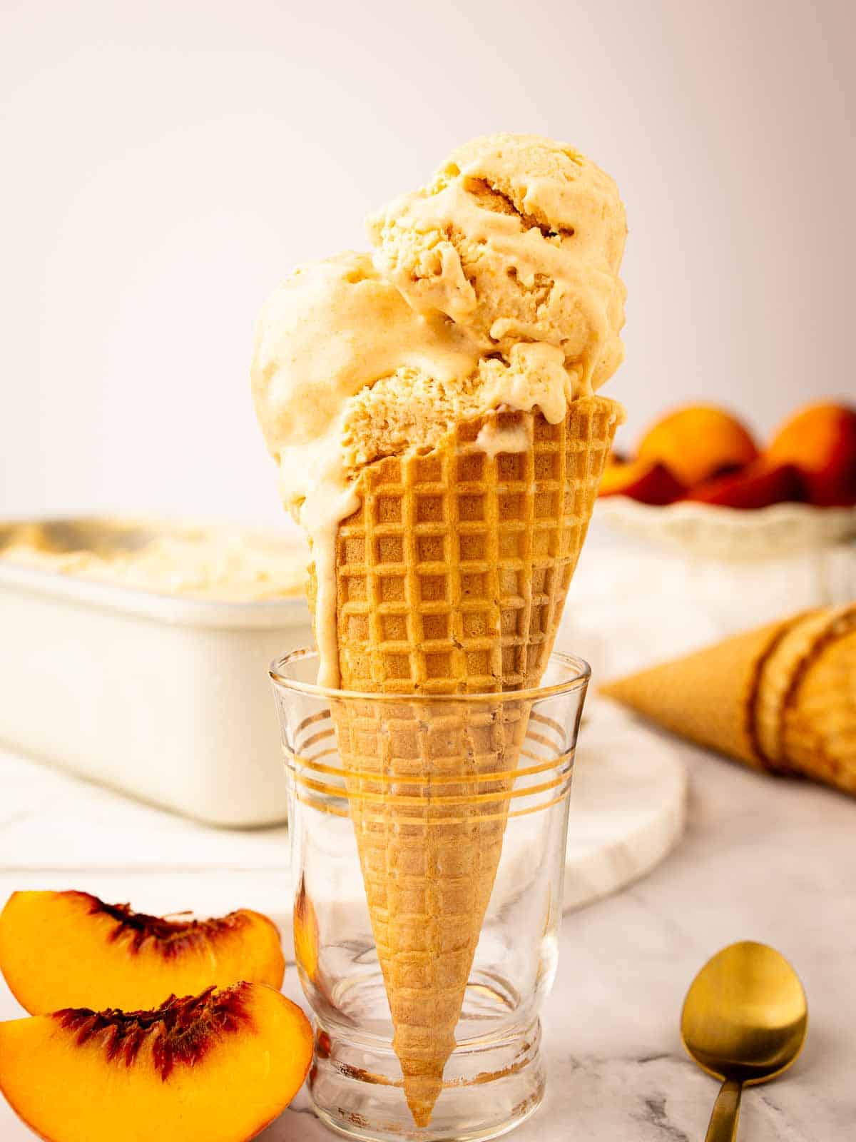 Prepared Peach Ice Cream Recipe scooped onto a cone.