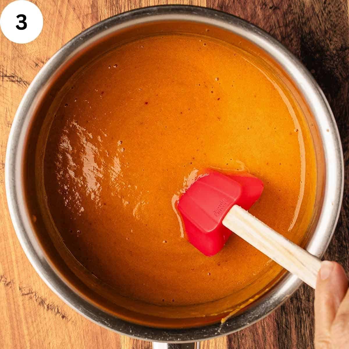 Stirring peach puree in a saucepan.
