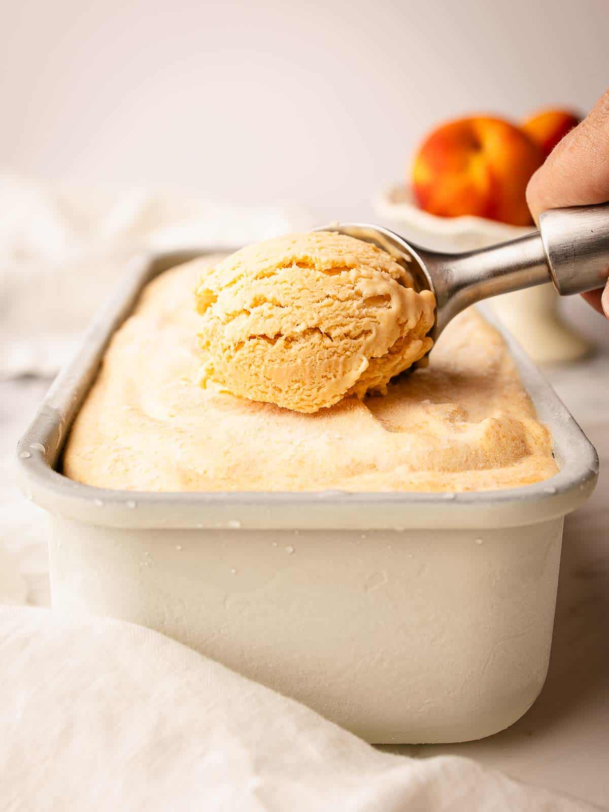 Scooping homemade peach ice cream viewed front on.
