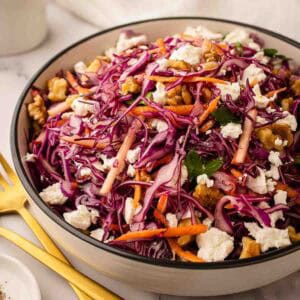 Red Cabbage Salad with red cabbage, grated carrot topped with feta in a round serving bowl.
