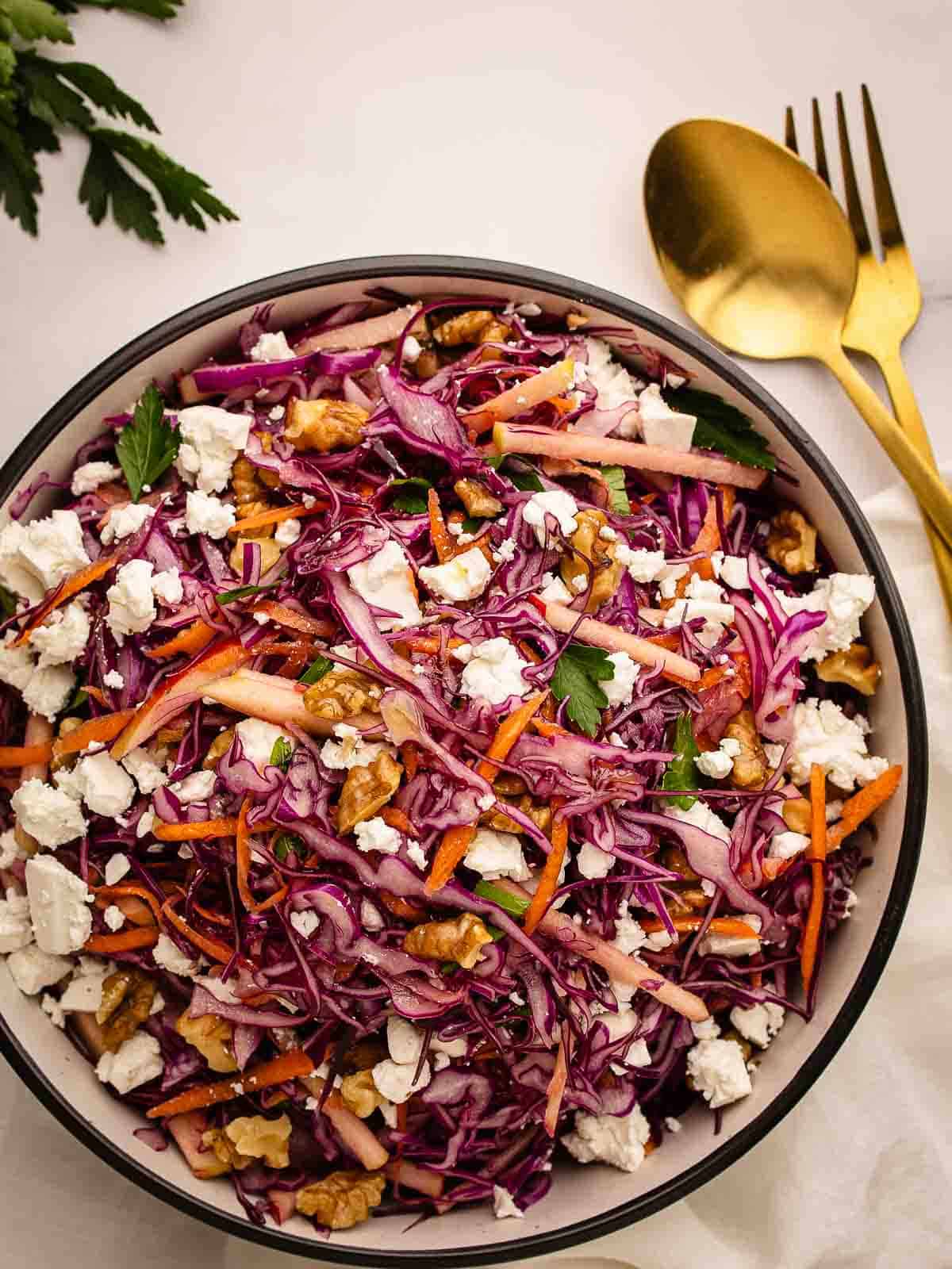 Overhead view of a salad of red cabbage, carrot and apple in a round bowl.