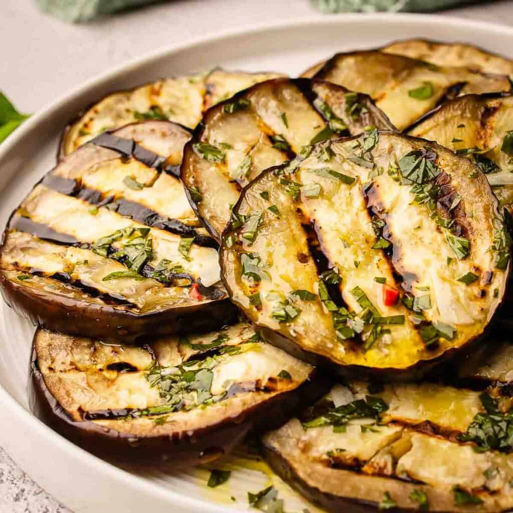 Grilled eggplant slices piled onto a round plate.