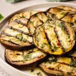 Grilled eggplant slices piled onto a round plate.