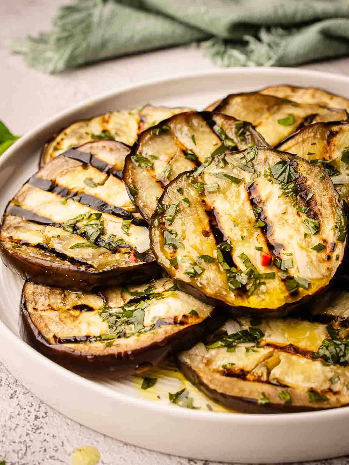Grilled eggplant slices piled onto a round plate.