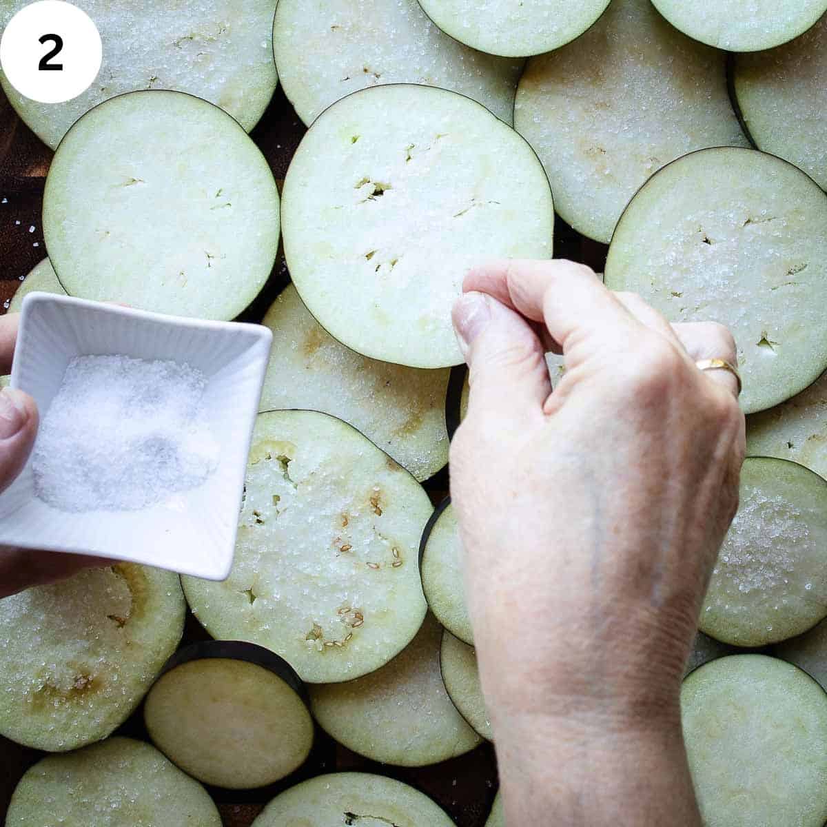 Sprinkling salt on eggplant slices.