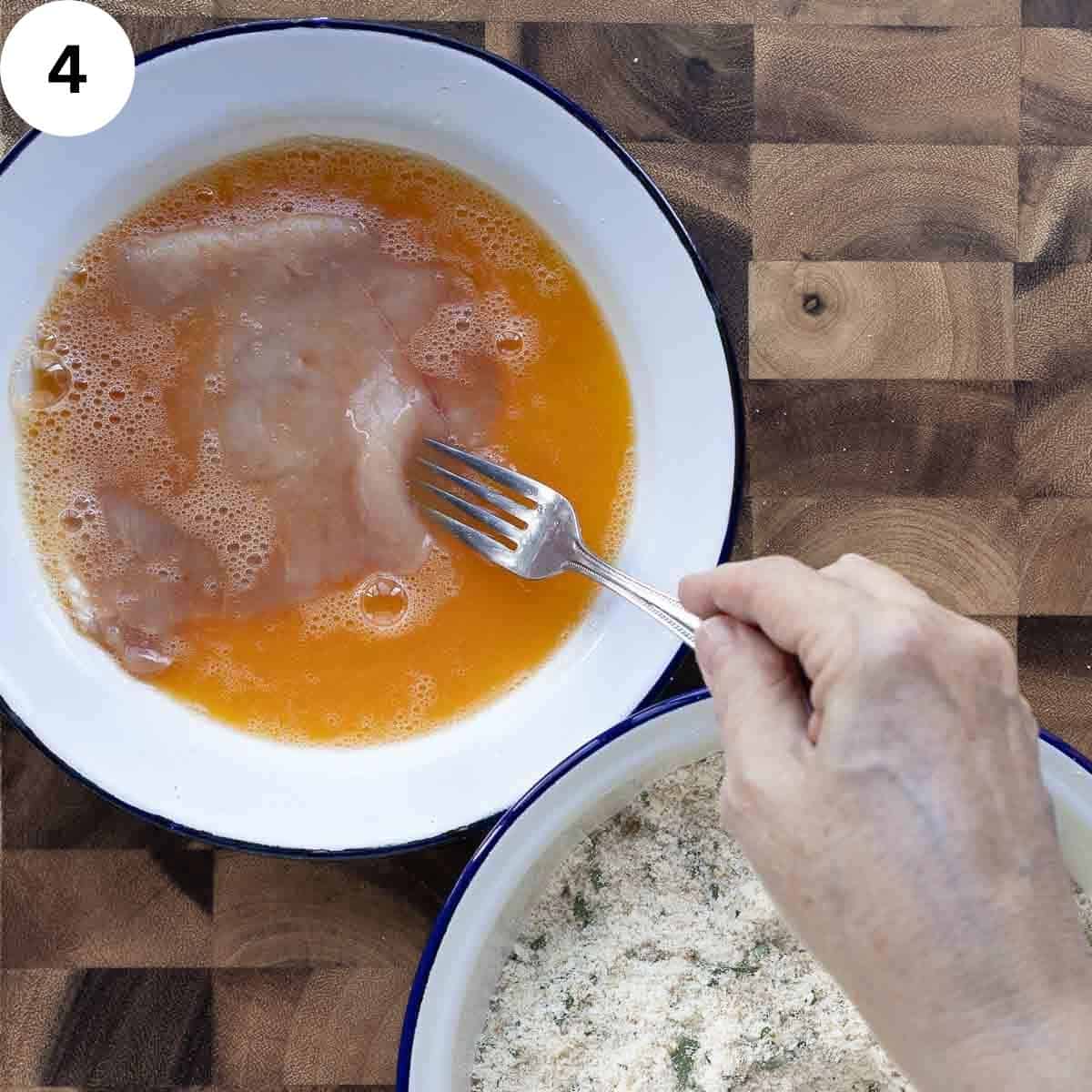 Dipping a cutlet into beaten egg.